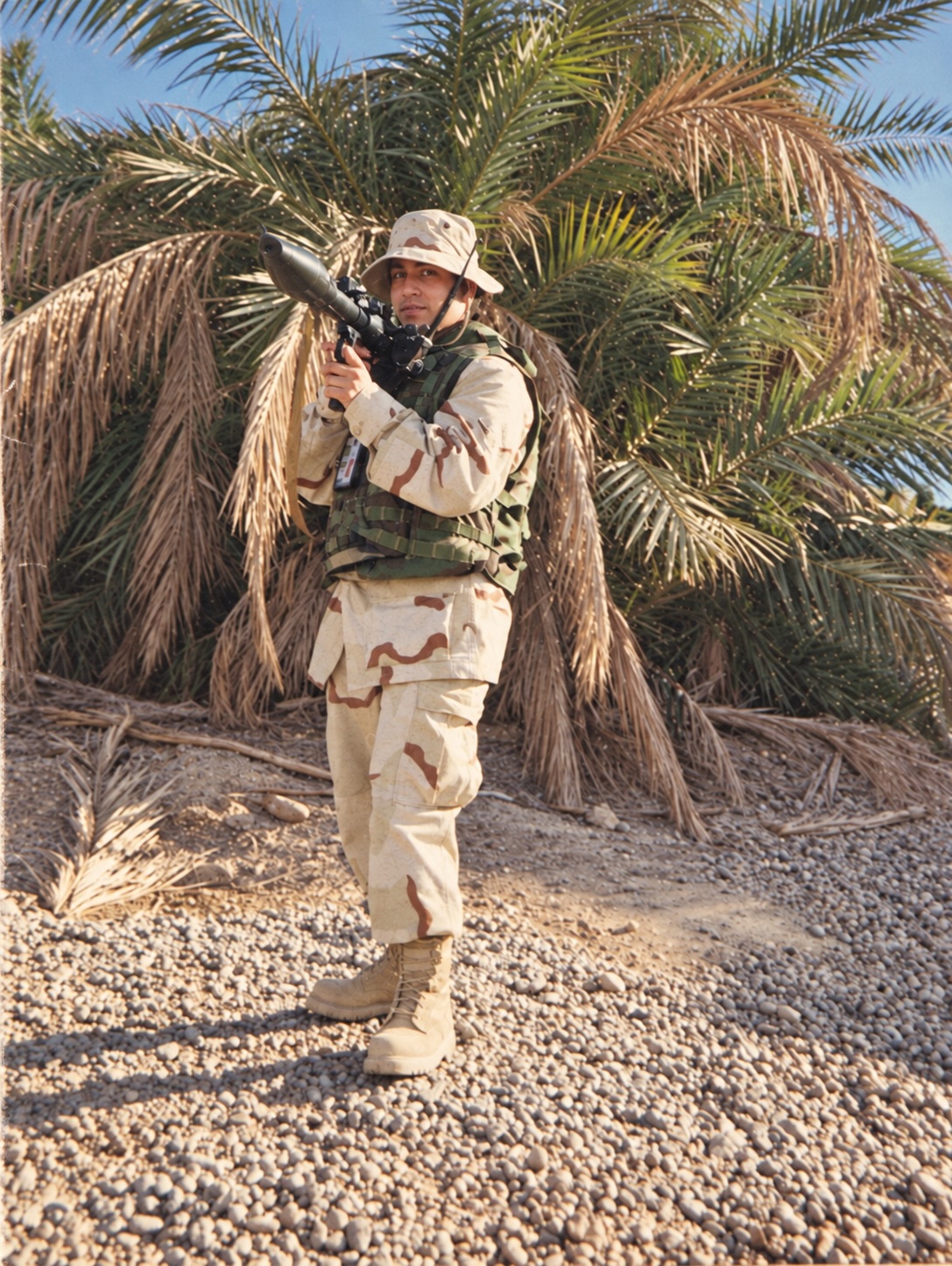 Dr. Remina Panjwani in a desert camouflage uniform and boonie hat, standing at her deployment site in Iraq